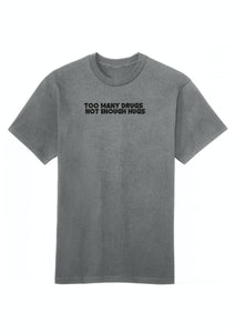 A gray cotton crew neck t-shirt with the text 'TOO MANY DRUGS NOT ENOUGH HUGS' printed on the front.