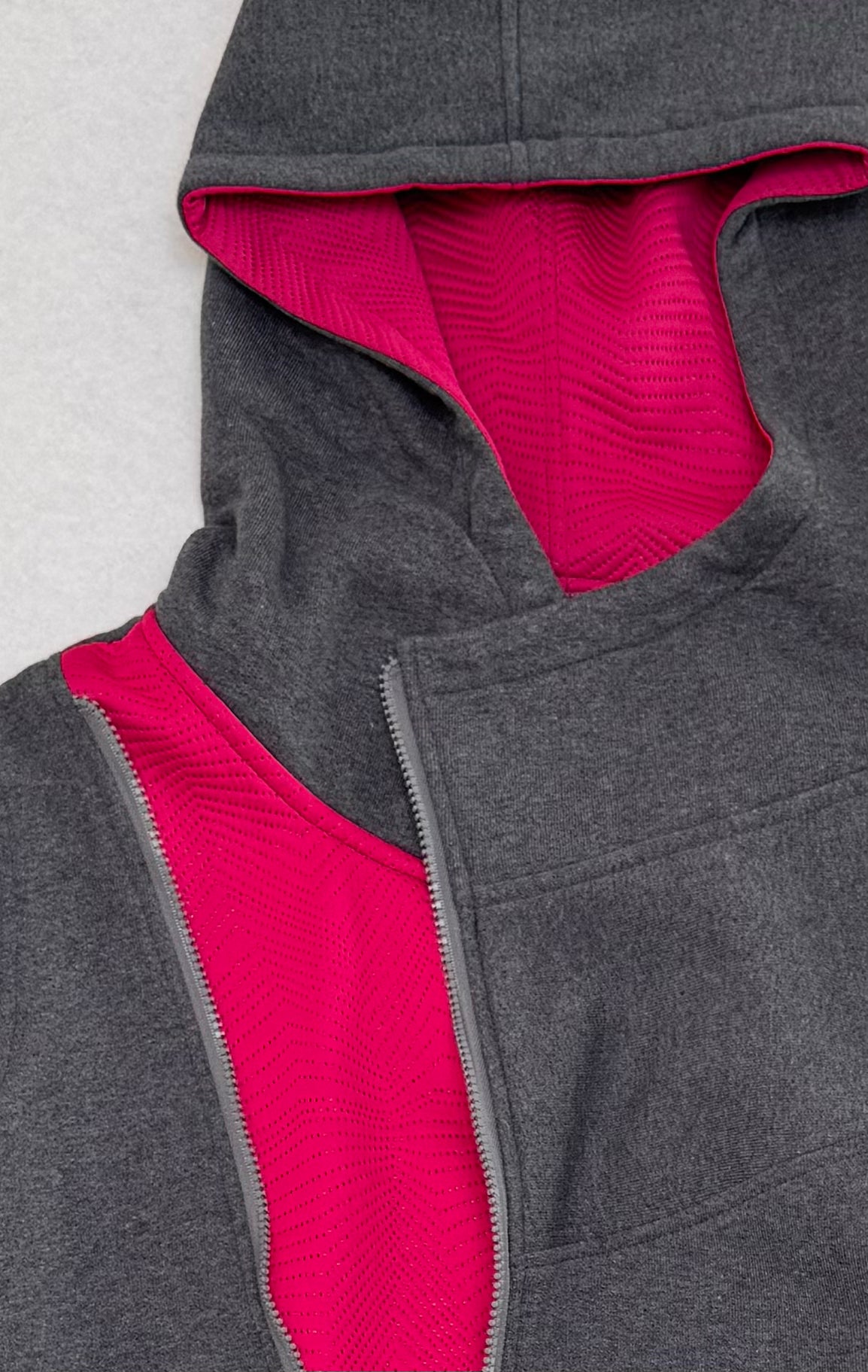 Gray and pink hooded jacket with textured lining on a light gray background