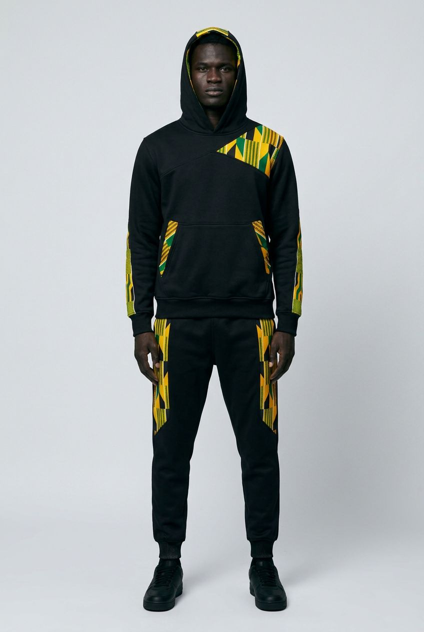 Person wearing a black hoodie and pants with yellow and green patterns on a white background