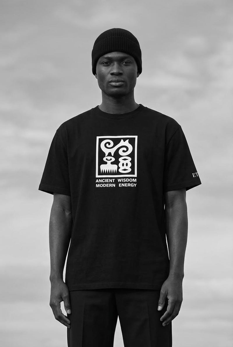 Person wearing a black t-shirt with a logo and text against a cloudy sky background